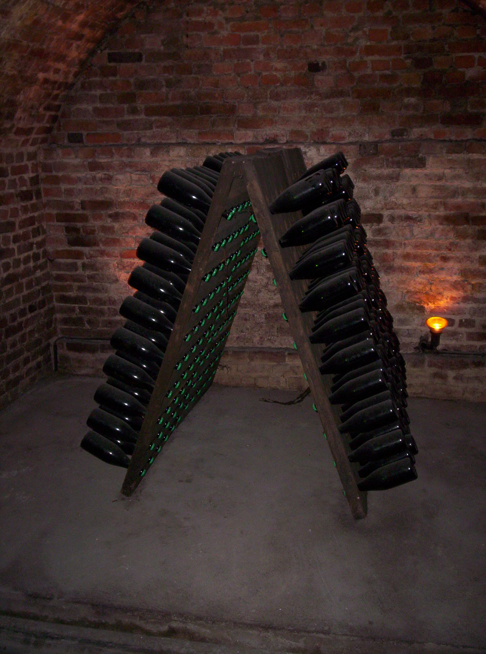 A riddling rack of champagne bottles resting in a brick cellar
